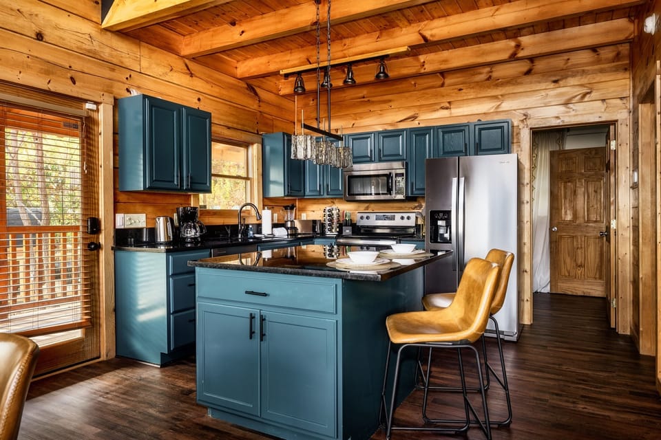 Cook in style in a fully equipped kitchen at Sunfyre Summit Cabin, featuring modern appliances, bold cabinetry, and plenty of space for unforgettable meals.