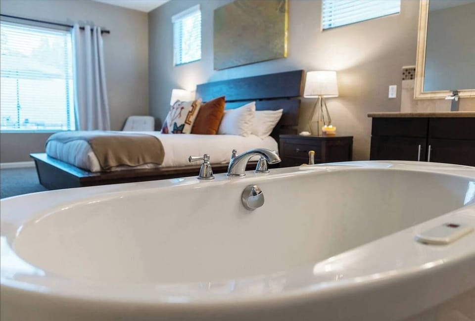 Elegant freestanding tub with a luxurious king bed backdrop for ultimate relaxation.