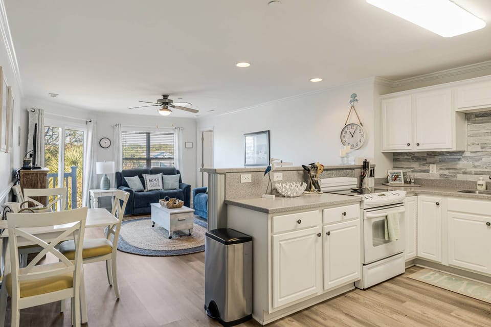 Upon arrival, you'll see our kitchen, welcoming living room, featuring a comfortable sofa, a TV for entertainment, and a ceiling fan to keep you cool.