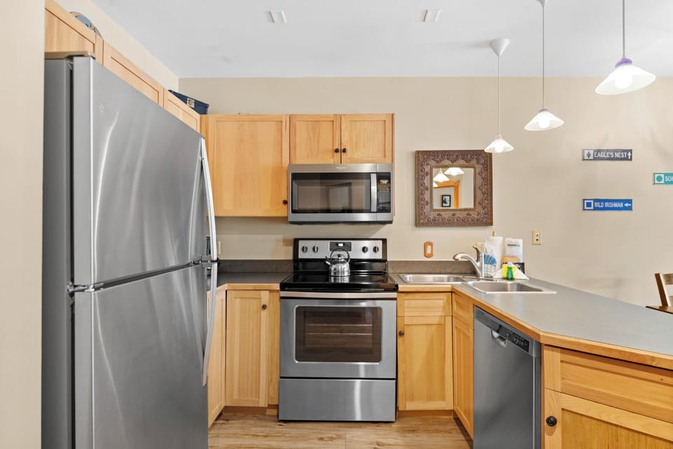 Your fully equipped kitchen features stainless steel appliances and warm wood cabinetry, perfect for preparing meals during your mountain getaway.