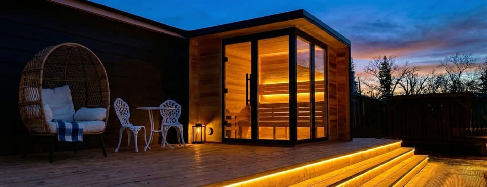 Modern outdoor sauna on a wooden deck with soft light. Sauna use at extra cost.