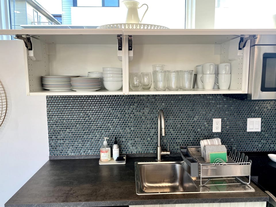 The cabinets are stocked with plenty of glasses, plates, bowls, and cups. 