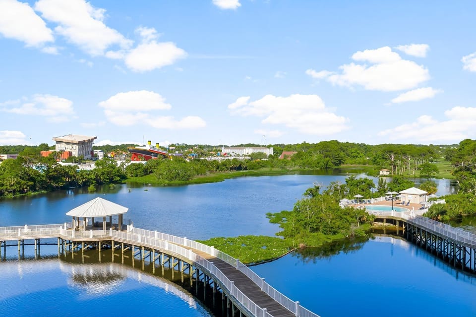 Scenic view of a waterfront boardwalk surrounded by lush greenery and calm waters.