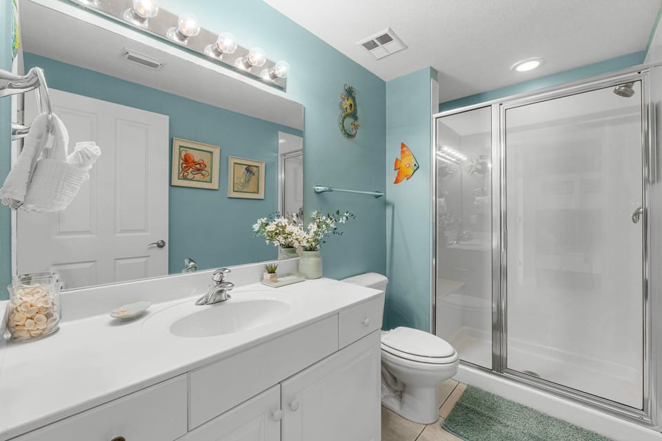 Modern bathroom with a glass-enclosed shower and coastal-themed decor.