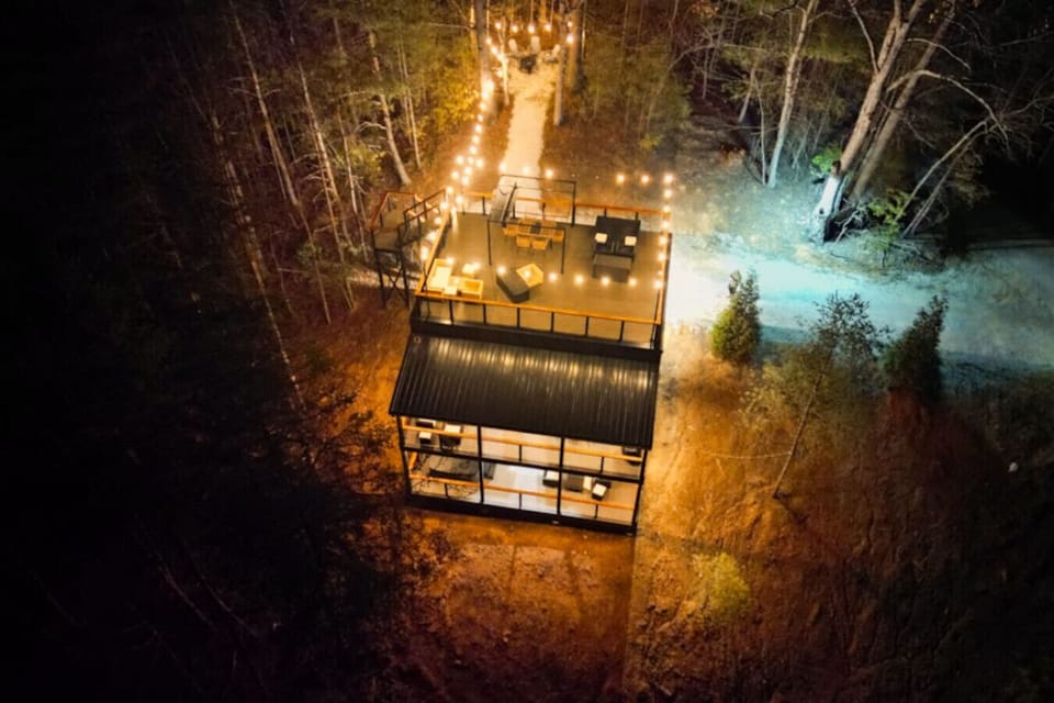 See the cabin come alive at night with a beautifully lit rooftop deck and peaceful forest setting