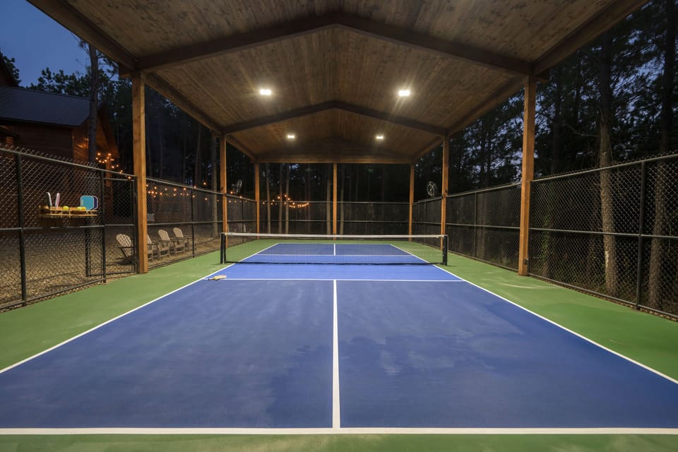 Indoor pickleball court with blue surface, wood roof & cozy lounge—play anytime