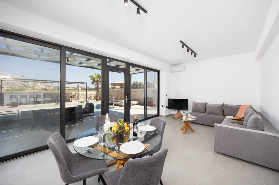 Open-plan living room with sofa, dining area, kitchen, A/C, WiFi internet, and satellite TV