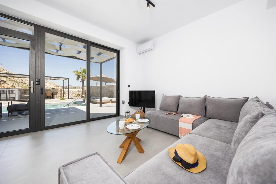 Open-plan living room with sofa, dining area, kitchen, A/C, WiFi internet, and satellite TV
