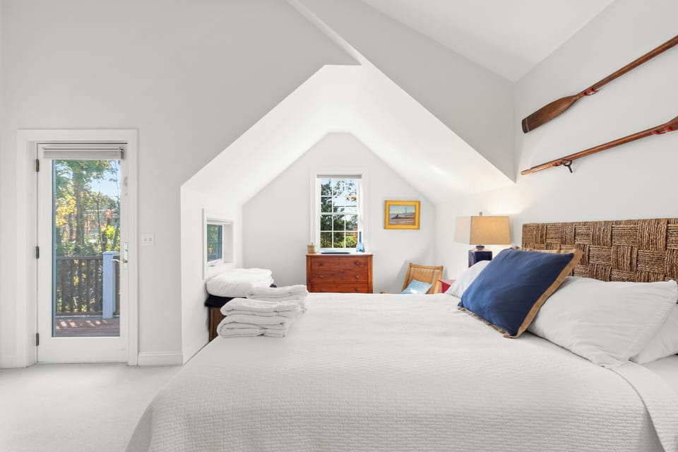 A bright bedroom with a window, darkening shades, and fresh linens.