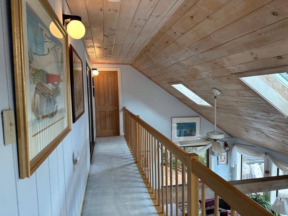 "The catwalk hallway at the top of the stairs, leading to the two bedrooms, and the second living area-