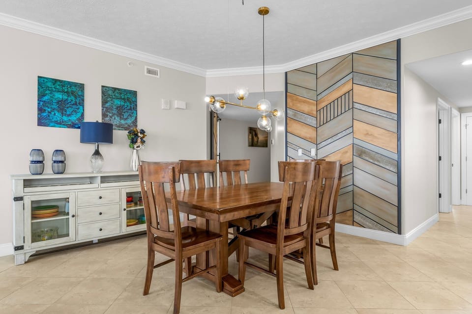 Dining area with a wooden table and chairs featuring a modern geometric accent wall.