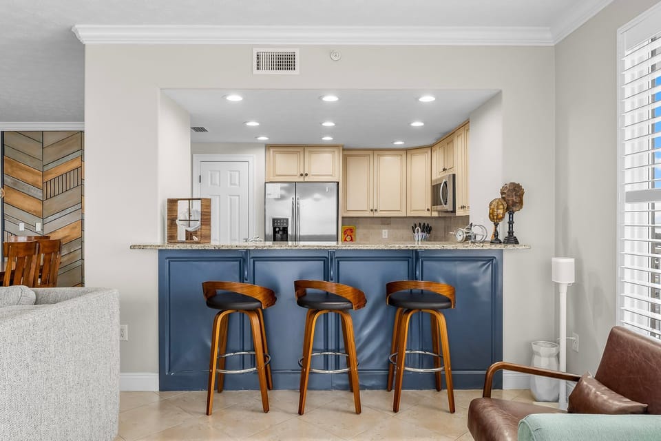 Modern kitchen with a blue breakfast bar and wooden stools for casual dining.