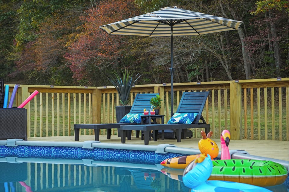 Lounge poolside under the shaded umbrella, surrounded by nature's tranquility.