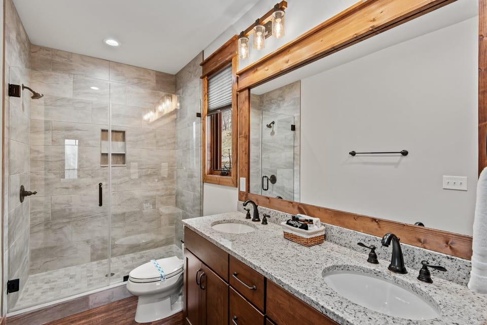 Double sinks, granite counters, and a glass walk-in shower make mornings easy at Cornerstone Cabin At Eagles Nest.