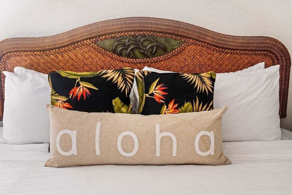 Woven wooden headboard with tropical floral pillows and “aloha” accent