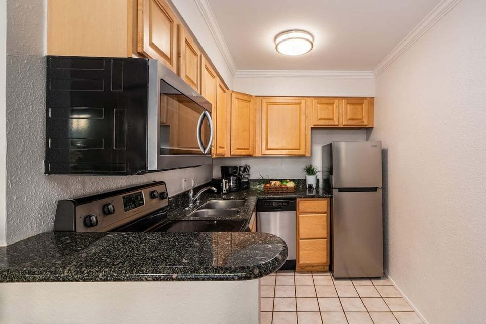 Modern kitchen with granite counters, wooden cabinets, and stainless fridge.