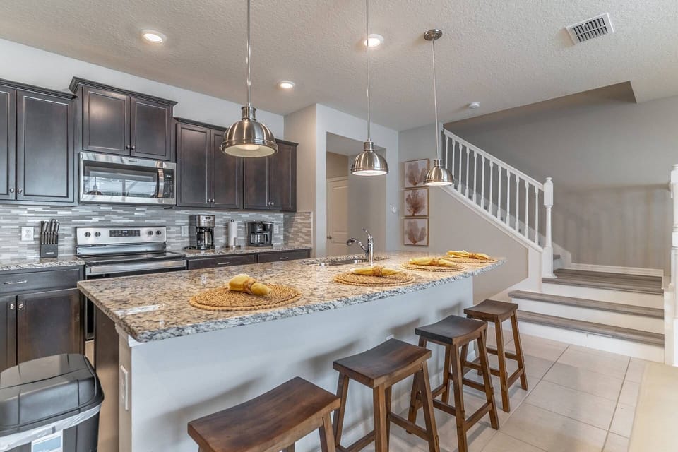Upgraded and fully stocked kitchen with granite counter, stainless steel appliances & island seating for 4