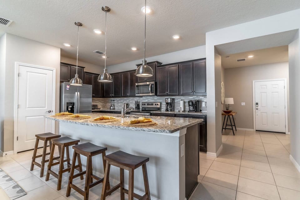Upgraded and fully stocked kitchen with granite counter, stainless steel appliances & island seating for 4