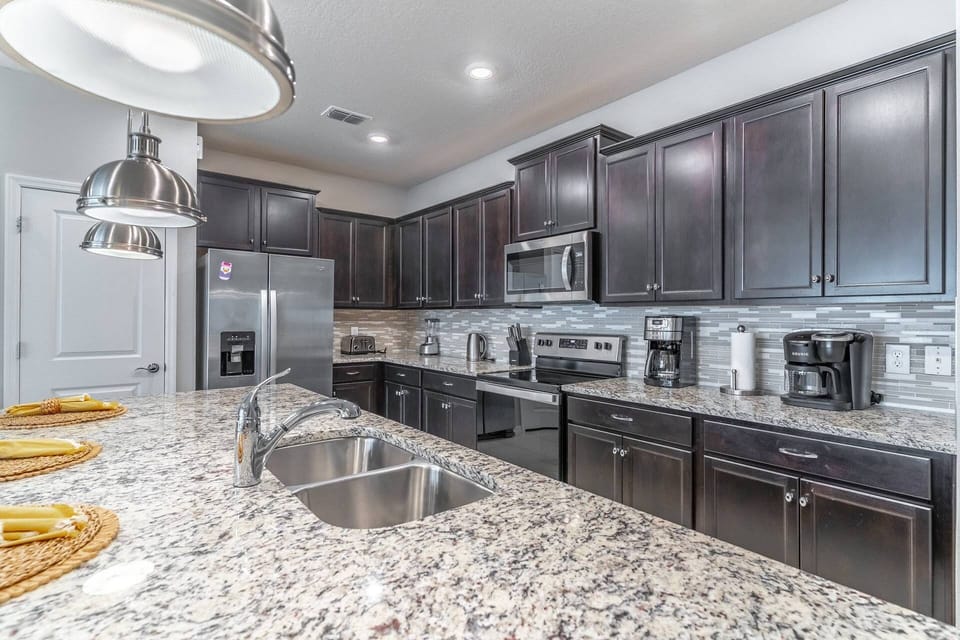 Upgraded and fully stocked kitchen with granite counters and stainless steel appliances