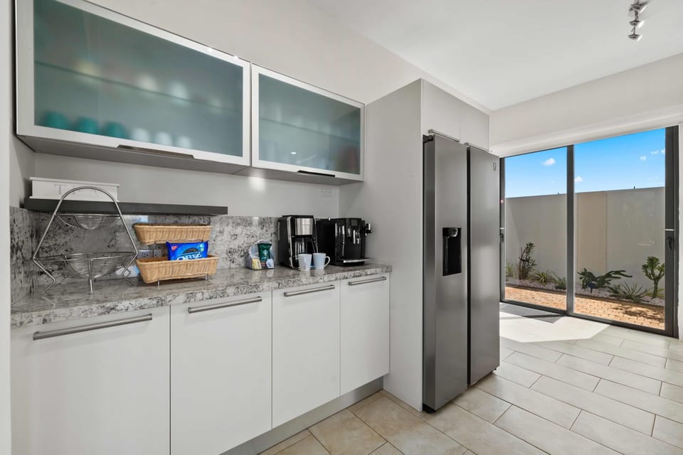 A sleek kitchenette equipped with modern appliances, including a coffee station to kick-start your mornings - Chic glass cabinetry adds elegance to functional storage space - With easy access to the outdoors, it’s convenience meets style