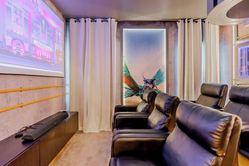 Enjoy cinematic nights in this stylish media room, featuring plush black leather recliners that invite relaxation. Soft curtains frame a large screen, while vibrant artwork adds a touch of personality to this cozy retreat.