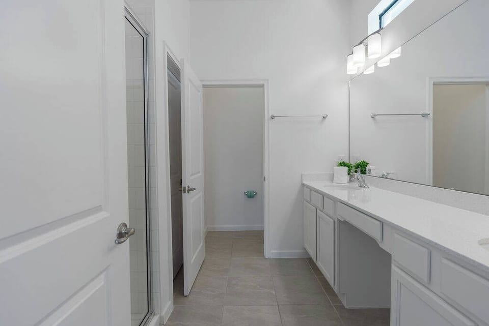 Experience a bright, airy bathroom with a spacious double vanity and sleek white countertops that invite relaxation. Natural light floods in, enhancing the clean lines and modern finishes for a refreshing atmosphere.