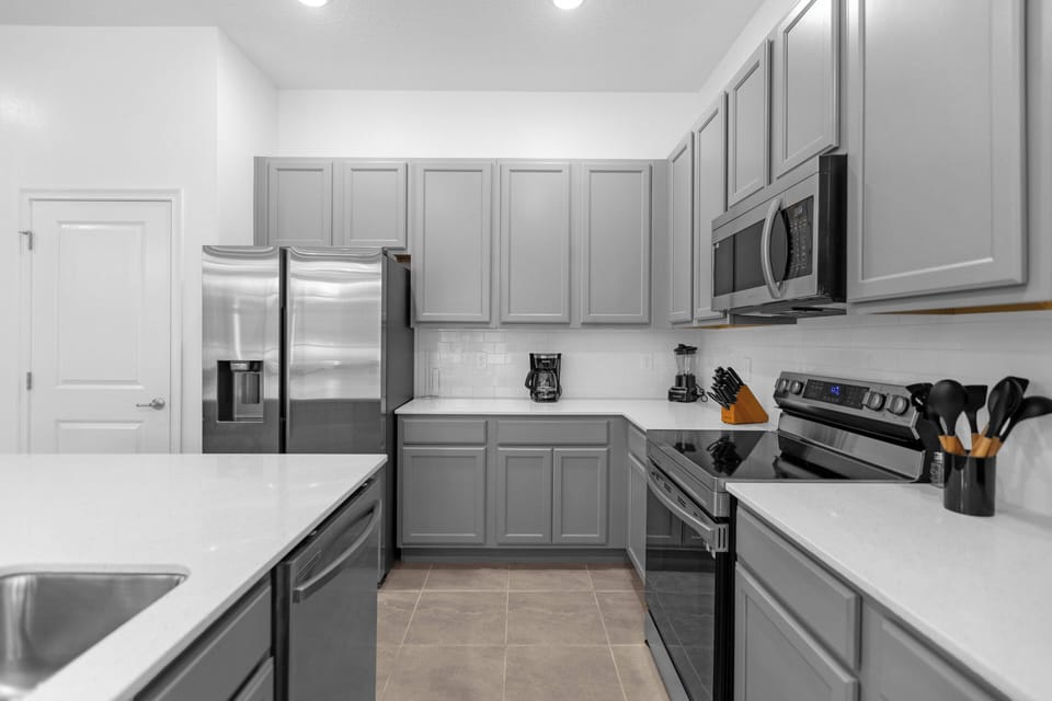 This bright kitchen boasts sleek gray cabinetry and modern stainless steel appliances, creating a perfect space for your culinary adventures with clean lines and plenty of counter space for whipping up delightful meals.
