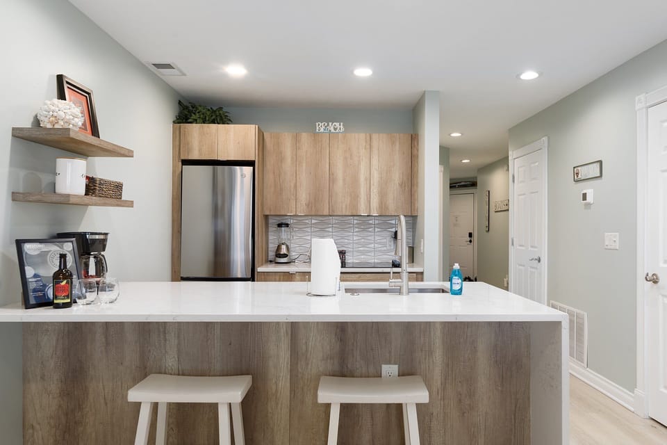 Sleek kitchen island w/ barstools, ample counter space & stainless steel appliances.