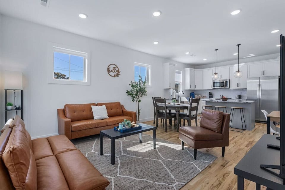 Bright, inviting space with two sleek leather couches, a lounge chair, flat-screen Roku TV, and a dedicated workspace. Great for game nights, movie marathons, or lazy days in.