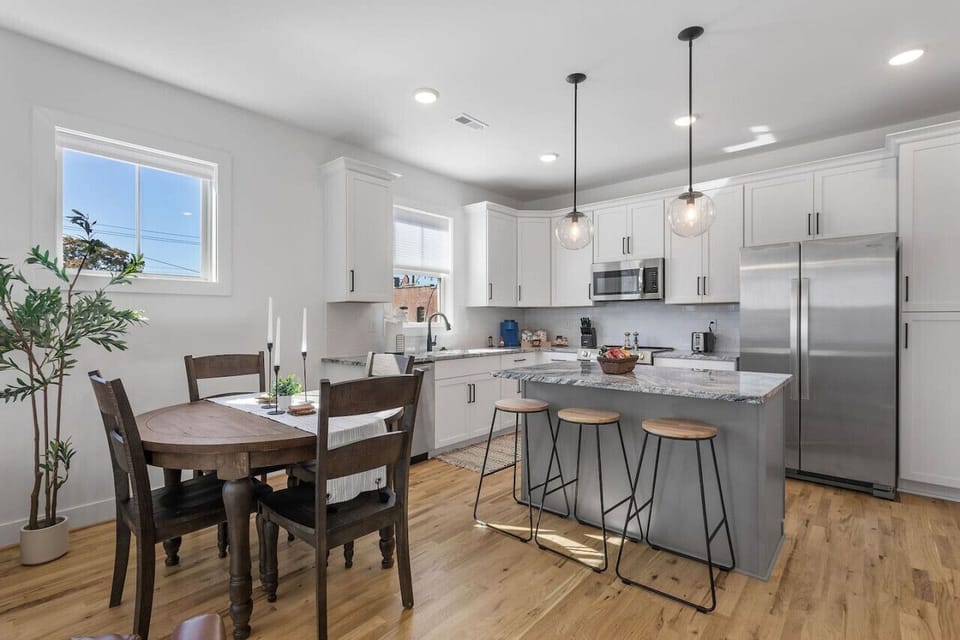 A modern, fully-equipped kitchen with a spacious island, perfect for meal prep and gatherings. Deep basin sink, ample counter space, and a sunny window view make cooking here a delight!