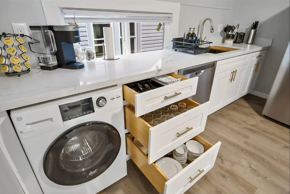 Modern kitchen with white cabinetry, a washing machine, a dishwasher, and all essentials neatly organized for your stay.