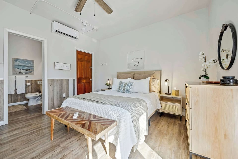Bright bedroom with modern wood flooring and an en suite bathroom.