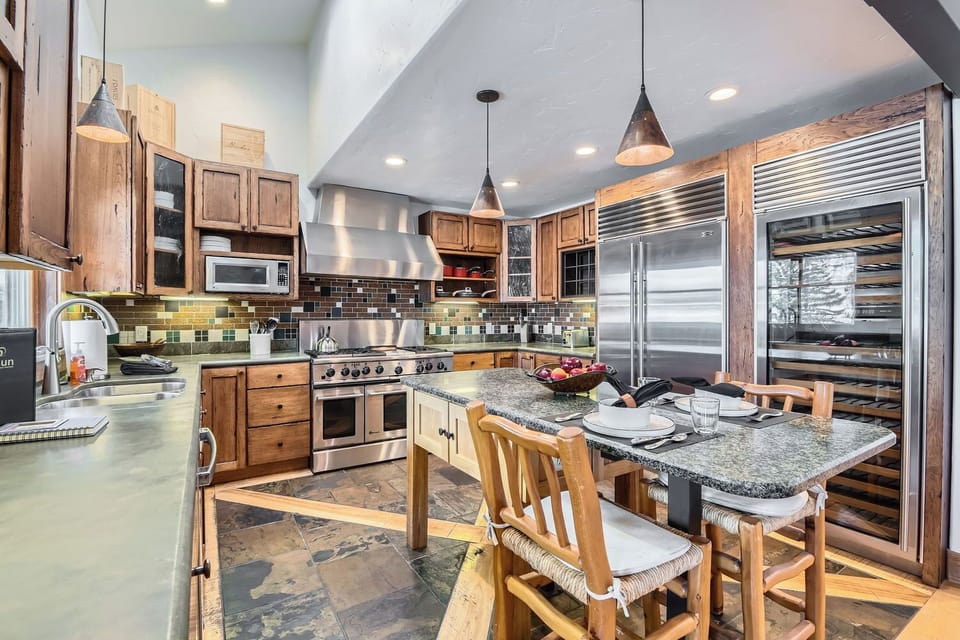 Cook in style in this fully equipped gourmet kitchen, featuring stainless steel appliances, a breakfast bar island, and warm wood cabinetry.