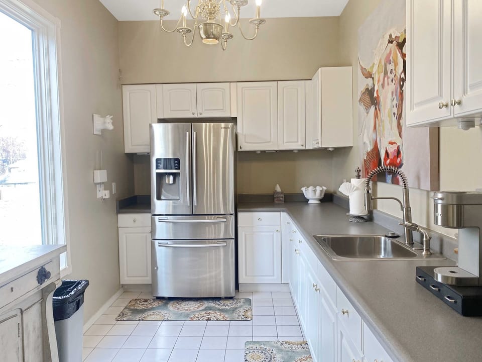 Bright kitchen with stainless steel fridge, white cabinets, and modern fixtures.