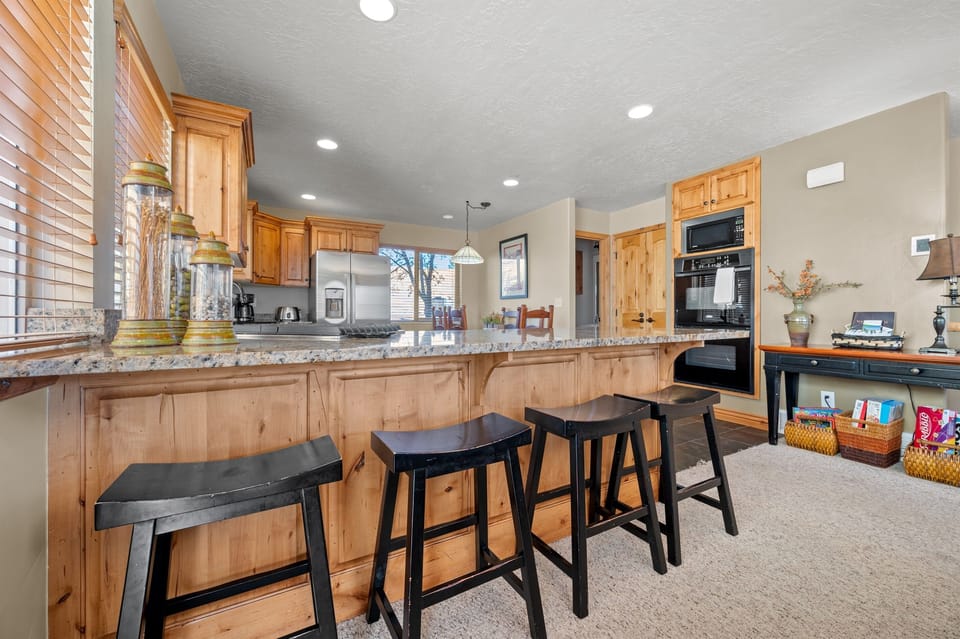 The gourmet kitchen features a breakfast bar with seating and is equipped with appliances, including a microwave, wall ovens, gas stove, and spacious refrigerator.