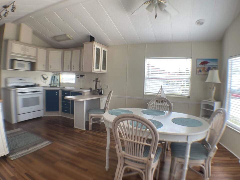 Kitchen with microwave, small island that is used for desk or food prep. 