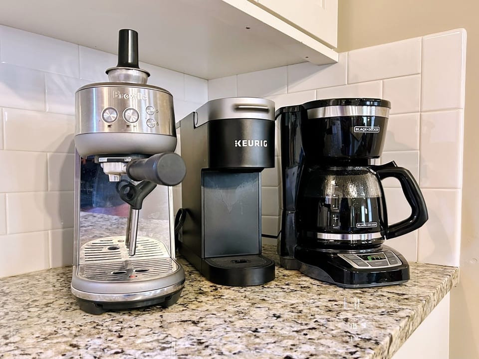 KCup machine, drip pot, bean grinder, espresso machine, and plenty of mugs