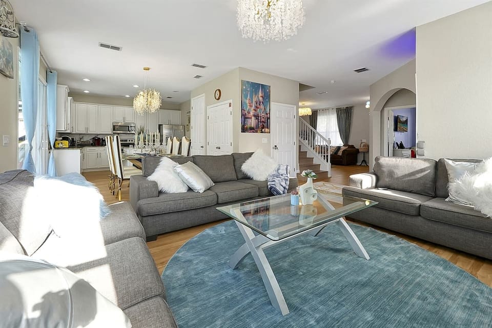 Spacious, open-concept living area with plush seating and elegant chandeliers—perfect for family gatherings or cozy evenings in.