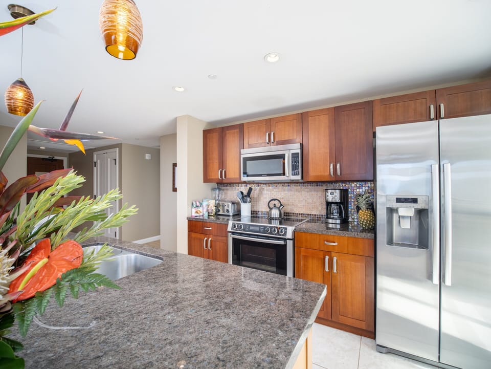 Enjoy the convenience of this sleek kitchen, equipped with stainless steel appliances, including a large fridge and microwave.