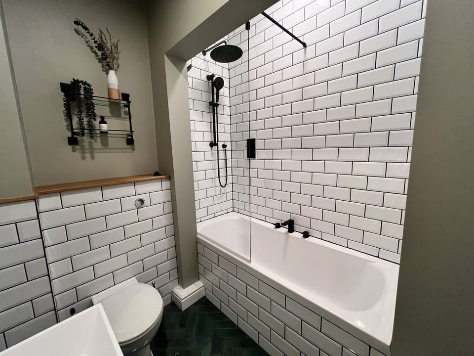 The bathroom comprises bath with overhead waterfall shower, WC, sink and heated towel rail