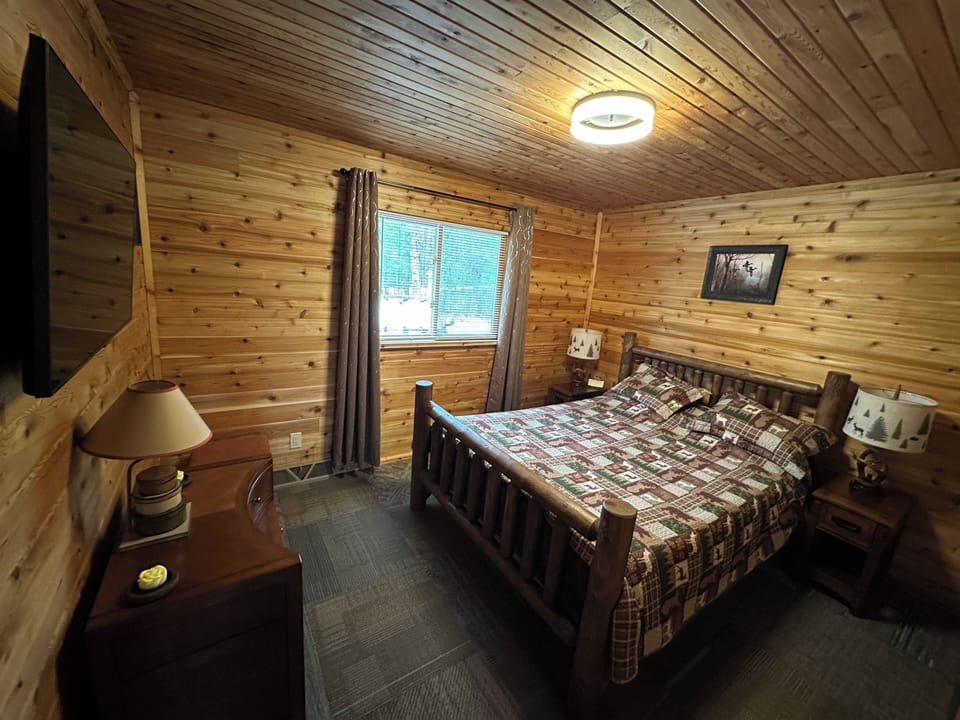 Main bedroom has a queen bed, nightstands, lights, and a TV.
