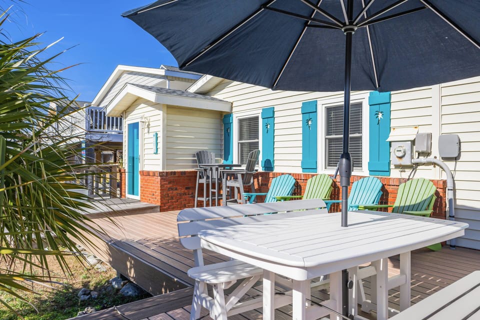 Outdoor deck with vibrant chairs and a shaded table, perfect for relaxing or dining al fresco.