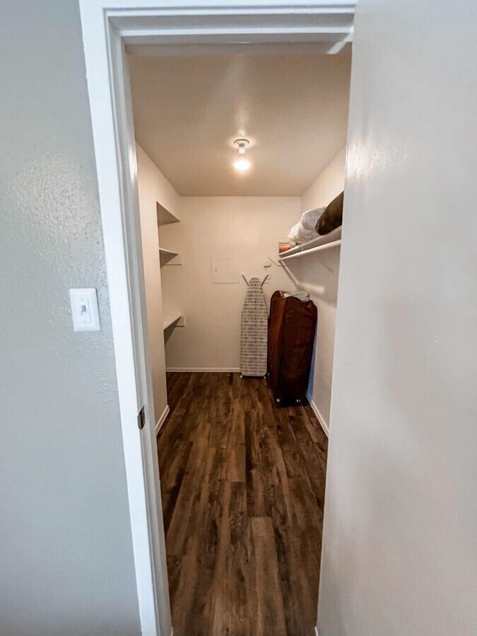 Store your belongings with ease in this spacious walk-in closet, complete with an extra foldable bed and ironing essentials.