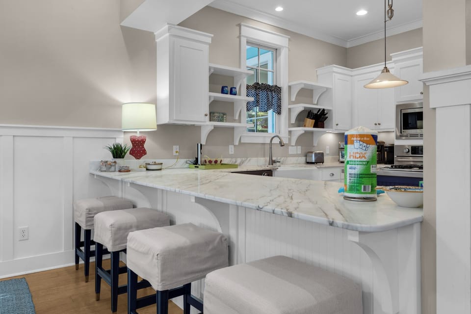 Your spacious kitchen features gleaming marble countertops, custom white cabinetry, and a welcoming breakfast bar where you can enjoy morning coffee.