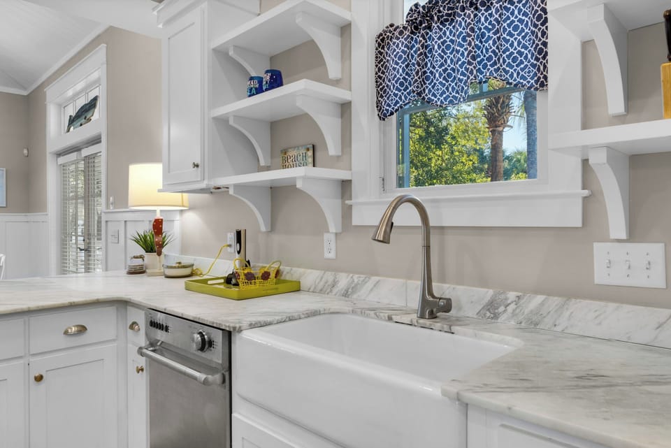 Your chef-inspired kitchen features marble countertops, farmhouse sink, and charming coastal details for memorable meal preparation.