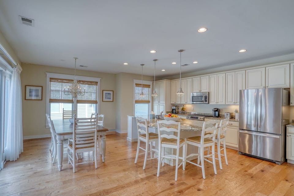 30220 Seaglass Way - Upscale Culinary Hub - The open-concept kitchen is a chef’s dream, featuring professional-grade stainless steel appliances, custom white cabinetry, and a large central island. Designer pendant lighting and beautiful hardwood floors tie the sophisticated space together.