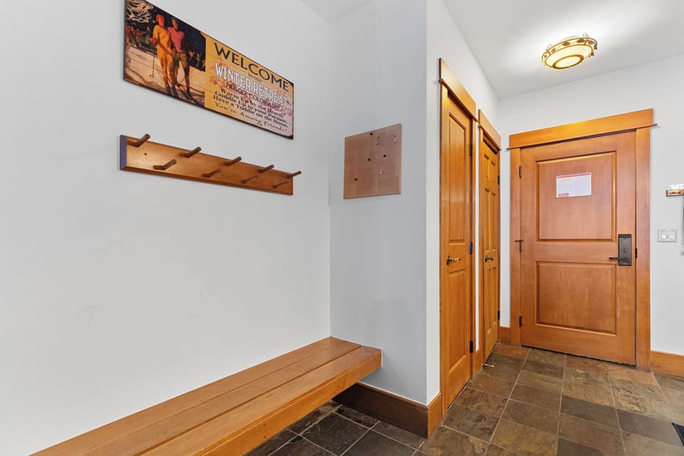 Step into your welcoming entryway with rustic charm—wooden bench, coat hooks, and ski-themed décor create the perfect mountain retreat atmosphere.
