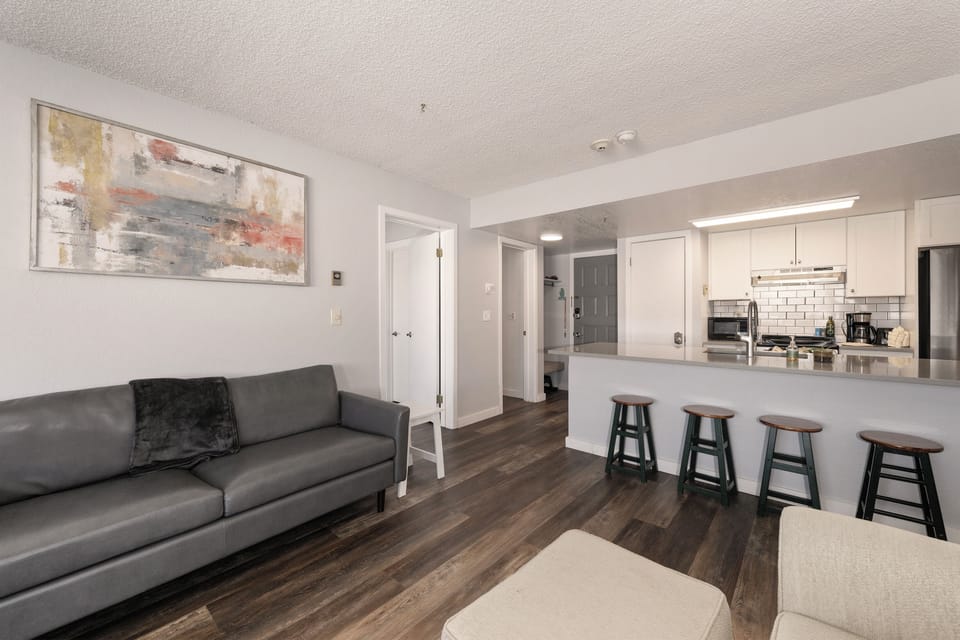 Unwind in your modern open-concept living space at Summit Unit 1103  where sleek kitchen meets cozy lounge, perfect for morning coffee at the breakfast bar.