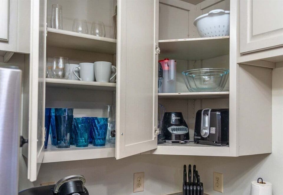 Open cabinets stocked with sparkling glassware and drink essentials ensure you have everything you need for a refreshing drink or a cozy evening in.