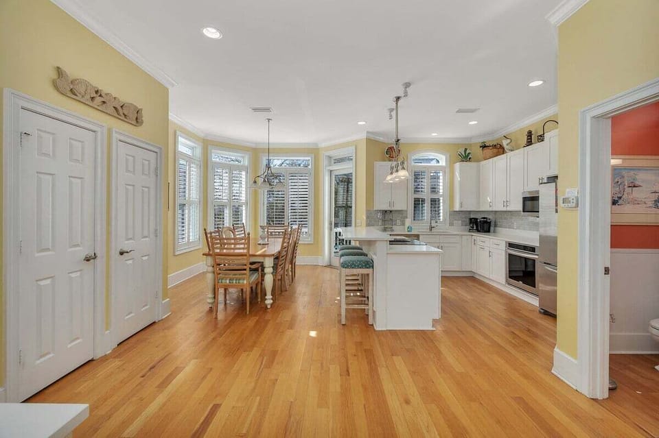 Open kitchen and dining area with white cabinets and hardwood floors